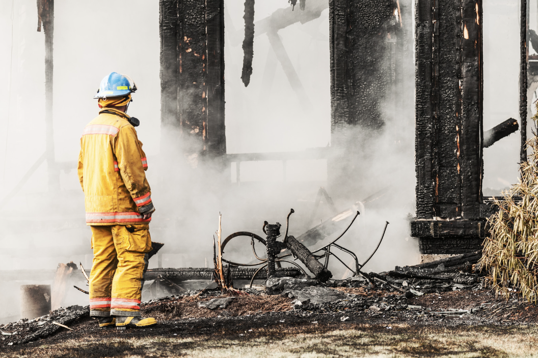 firefighter standing in front of burned house